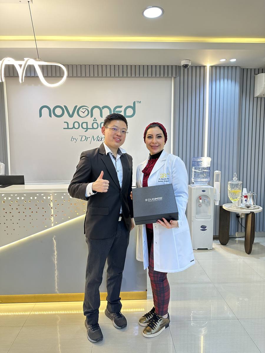 Dr Sin Yong with local physician at Novomed Clinic Dubai during ilooda KOL training visit — holding Dubimed gift
